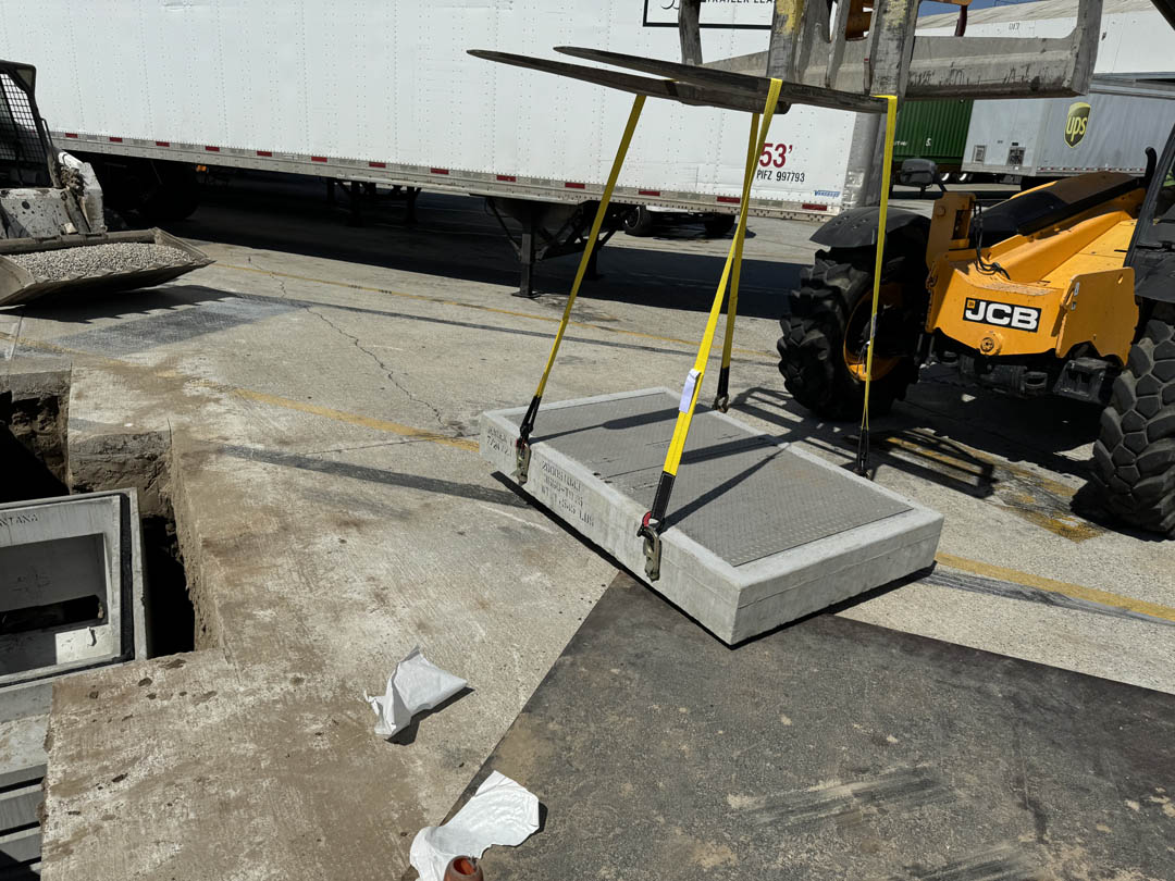 Open underground utility vault with conduit access at a construction site