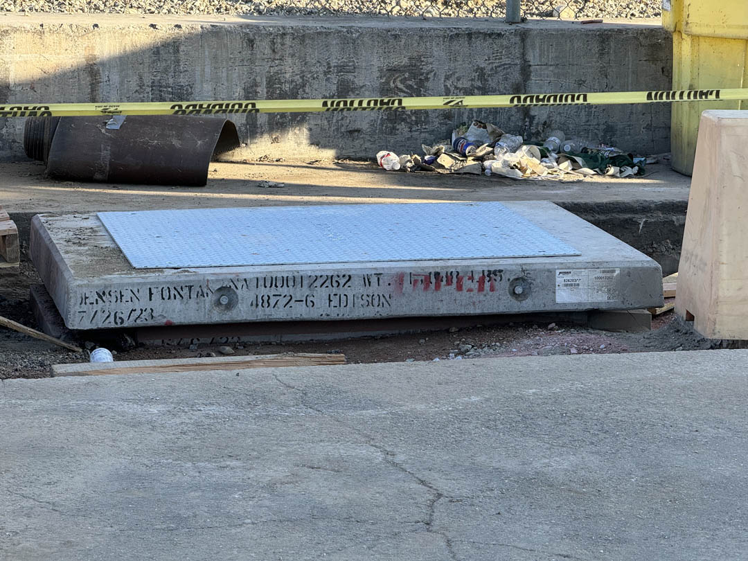 Concrete utility vault set into pavement with caution tape nearby