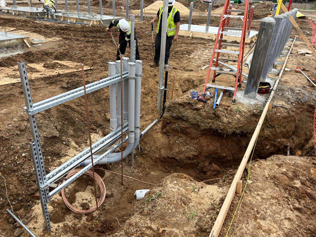 Workers installing conduits in an open utility trench