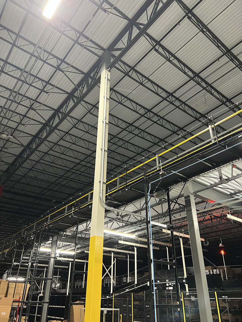 Vertical conduit runs and electrical cabinet mounted to a warehouse column