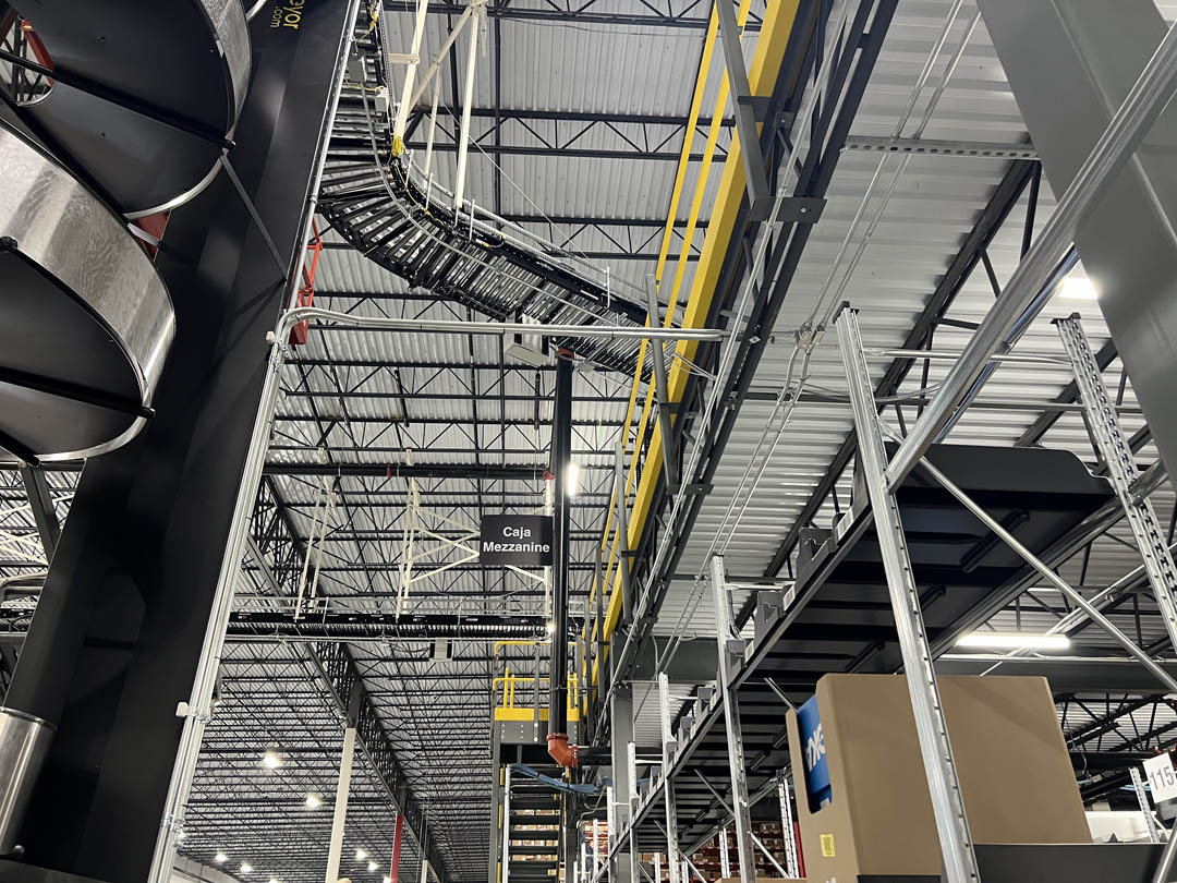 Overhead conveyor and electrical conduit above warehouse equipment