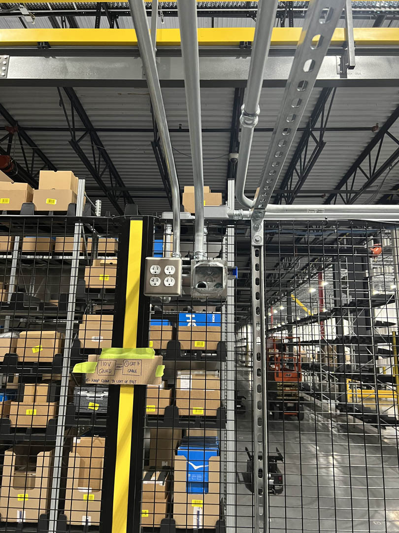 Vertical conduit and controls installed beside conveyor racking