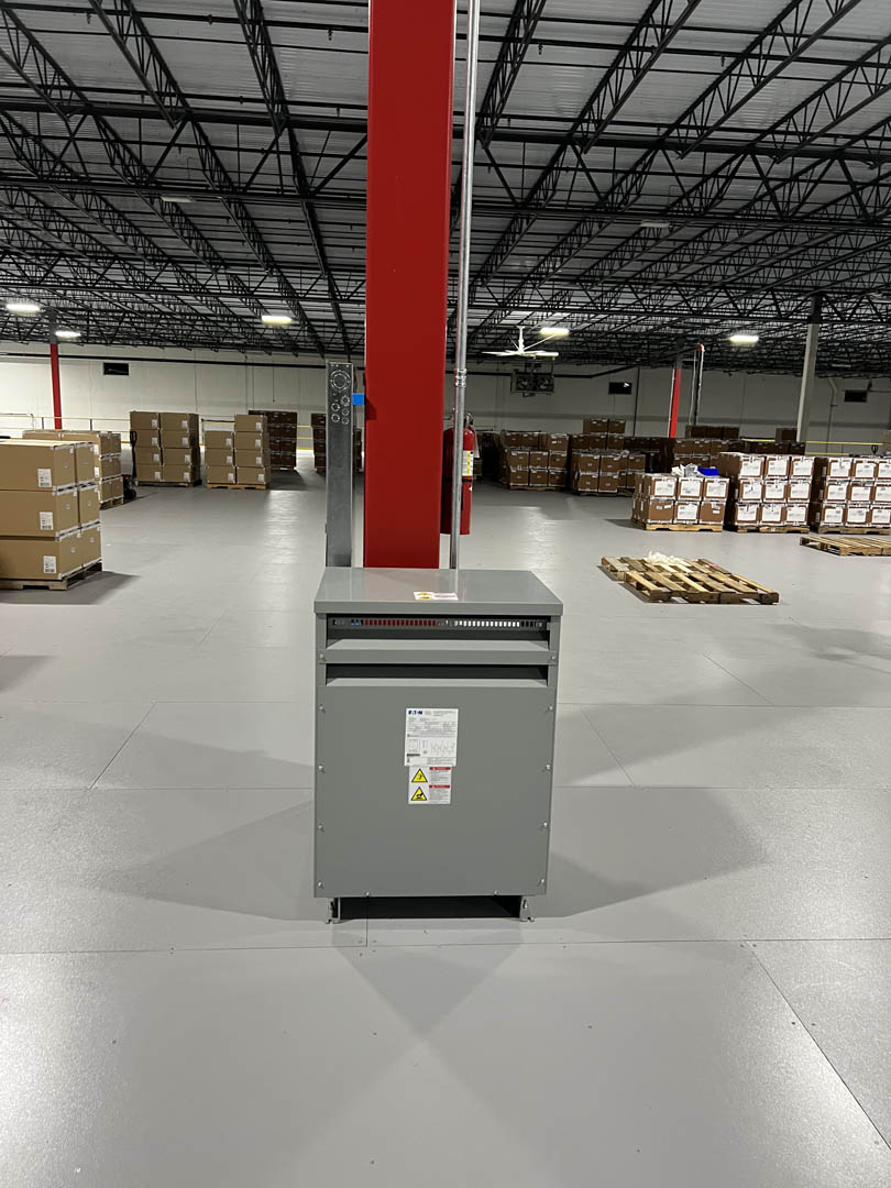 Floor-mounted electrical panel installed at a red warehouse column
