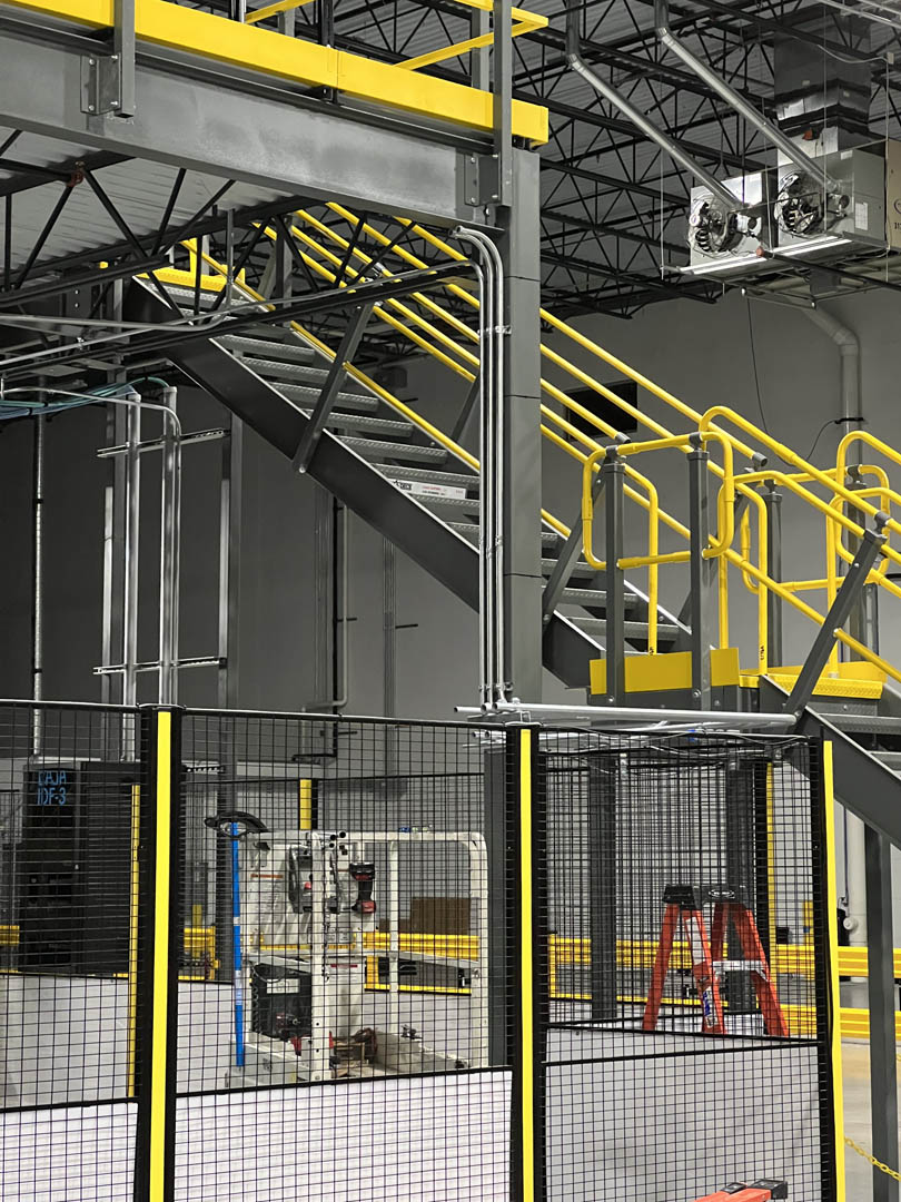 Elevated conveyor platform with yellow stairs and guardrails